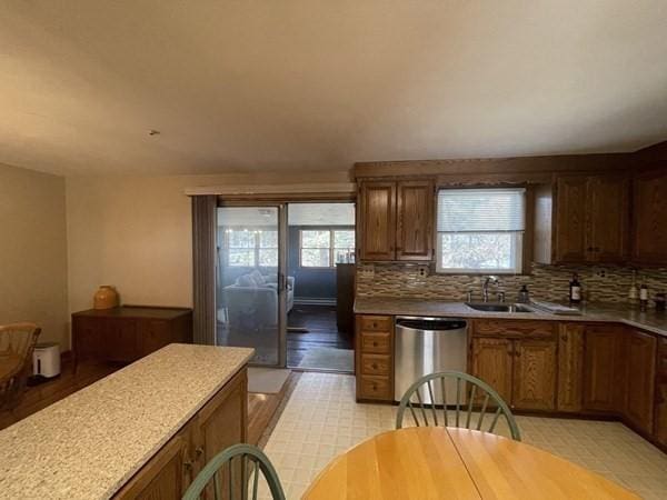kitchen featuring a sink, stainless steel dishwasher, tasteful backsplash, and a healthy amount of sunlight