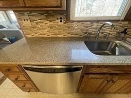 details with brown cabinets, a sink, backsplash, dishwasher, and light stone counters