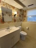 bathroom featuring vanity, toilet, and wallpapered walls