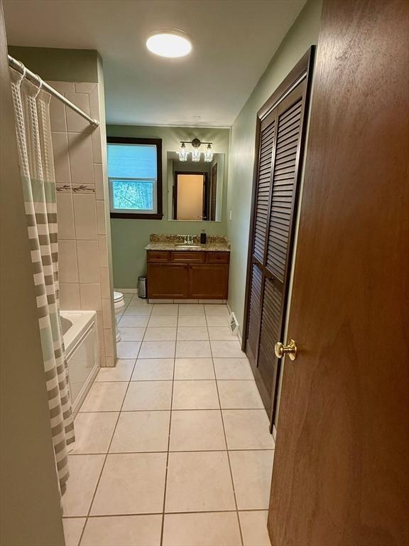 full bath featuring toilet, tile patterned floors, vanity, and shower / bath combo with shower curtain
