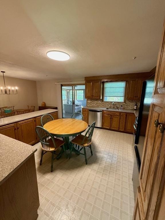 kitchen with brown cabinets, a sink, stainless steel dishwasher, backsplash, and light countertops