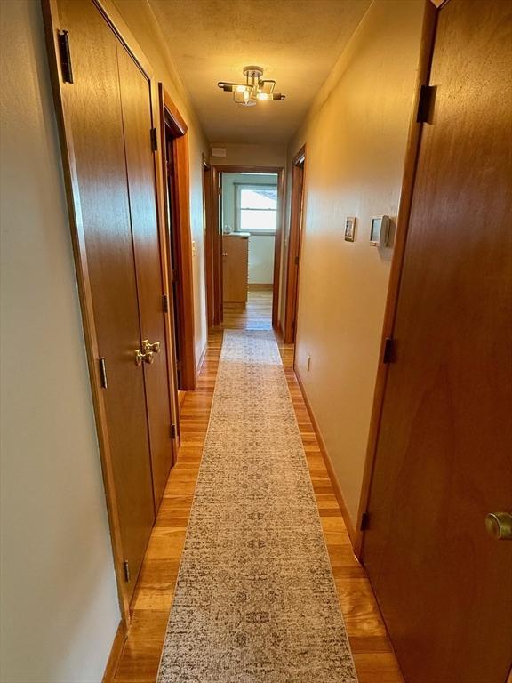 corridor featuring light wood-style flooring and baseboards