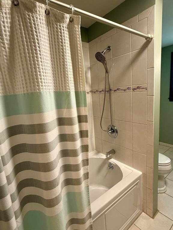 bathroom with tile walls, shower / bath combination with curtain, toilet, and tile patterned flooring