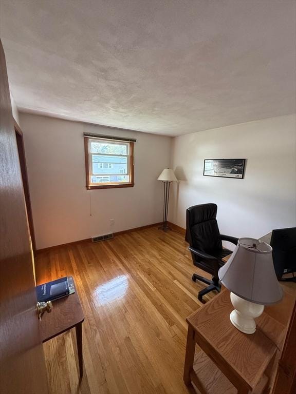 home office featuring baseboards, visible vents, and wood finished floors