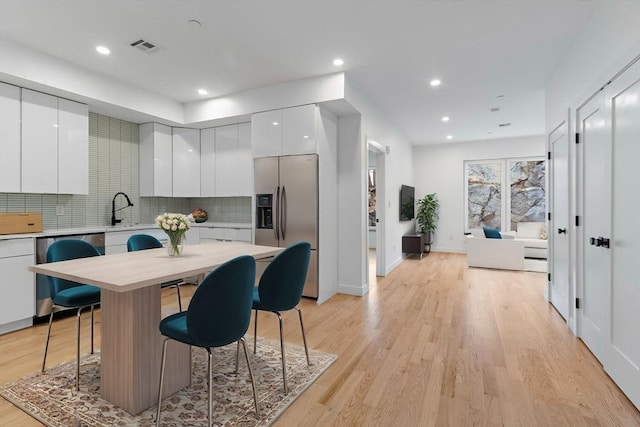 kitchen with white cabinets, a kitchen breakfast bar, tasteful backsplash, a kitchen island, and appliances with stainless steel finishes