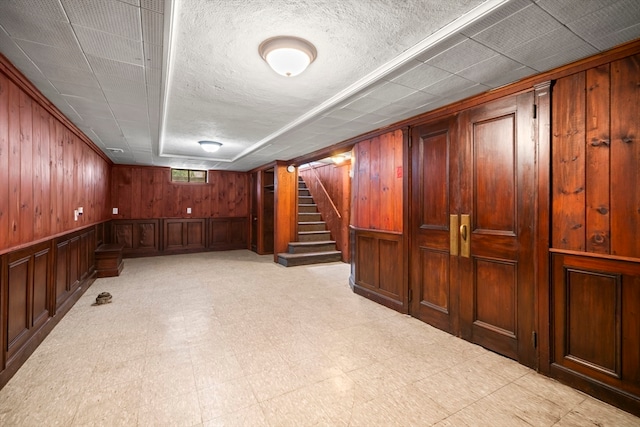 basement featuring wood walls and light tile patterned floors