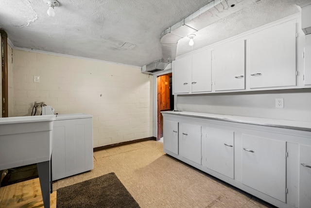 laundry area featuring sink, a textured ceiling, cabinets, and washer / dryer