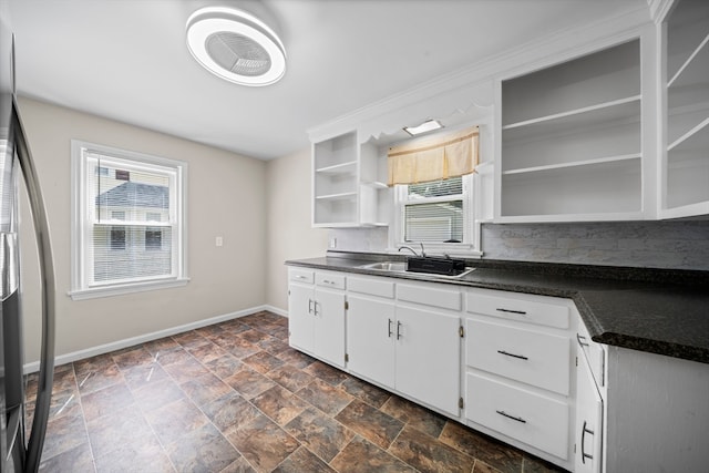 kitchen featuring white cabinets, stainless steel refrigerator, plenty of natural light, and dark tile patterned floors