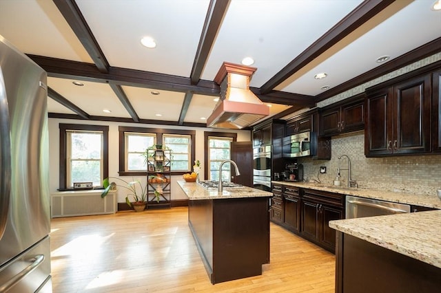 272 County St, Seekonk, MA 02771 - kitchen with appliances with stainless steel finishes, a sink, a center island with sink, decorative backsplash, and light wood-style flooring