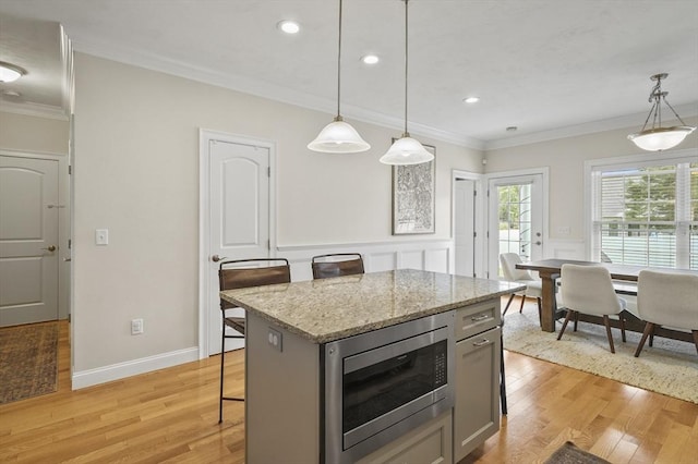 80 Edgemere Ave Unit 80, Northbridge, MA 01588 - kitchen featuring stainless steel microwave, a kitchen island, light wood-style floors, ornamental molding, and pendant lighting