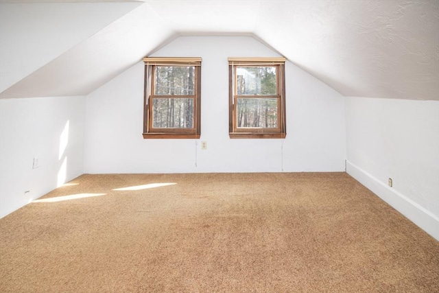 additional living space featuring lofted ceiling and carpet flooring