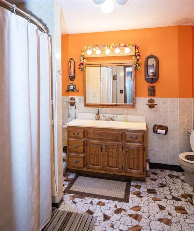 bathroom with tile walls, vanity, and toilet