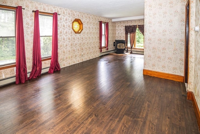 unfurnished room featuring hardwood / wood-style floors, a baseboard radiator, and a wood stove