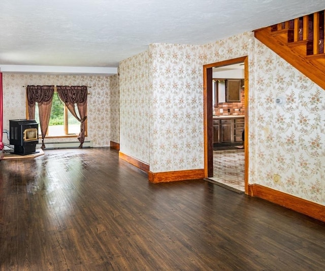 unfurnished living room with dark hardwood / wood-style flooring, a baseboard heating unit, a textured ceiling, and a wood stove