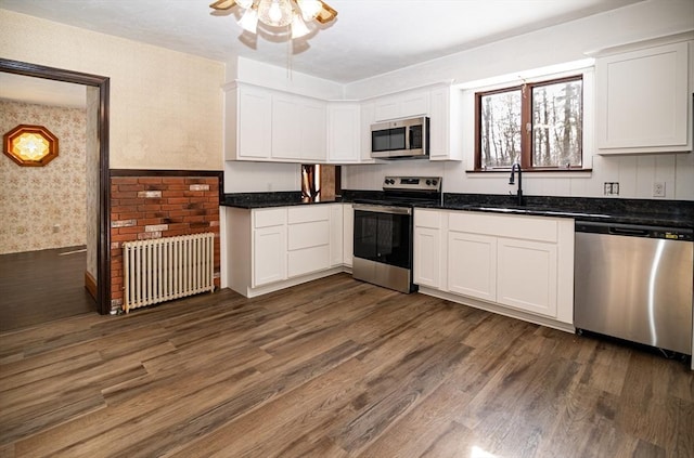 kitchen featuring white cabinetry, stainless steel appliances, dark hardwood / wood-style floors, and radiator