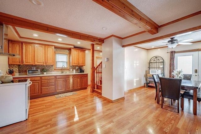 kitchen featuring a textured ceiling, light hardwood / wood-style floors, a healthy amount of sunlight, and white range