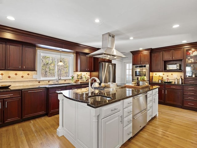 kitchen with stainless steel appliances, island range hood, sink, and a kitchen island with sink