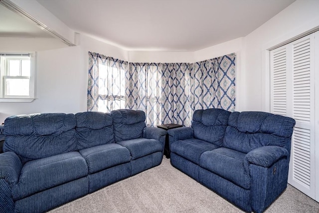 carpeted living room with beamed ceiling