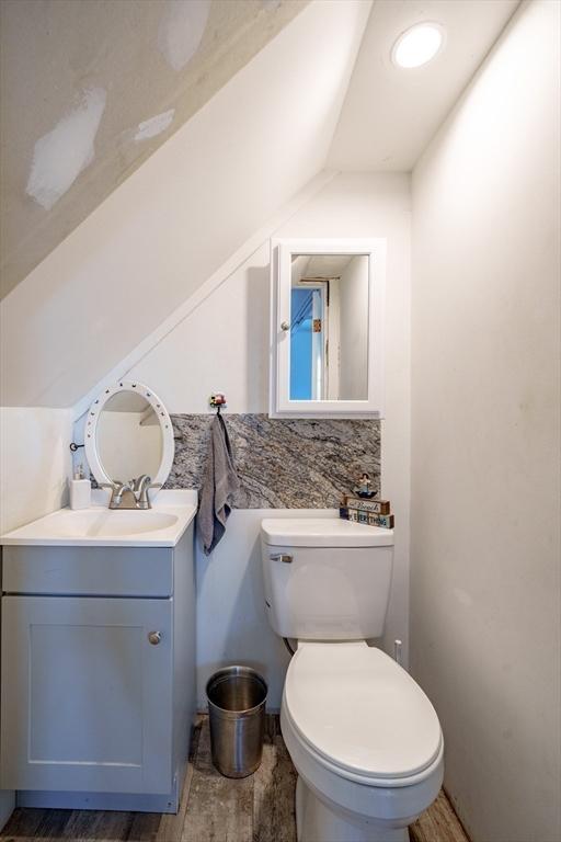 bathroom featuring hardwood / wood-style floors, vanity, toilet, and tasteful backsplash