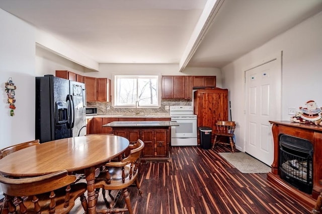 kitchen featuring a center island, backsplash, black refrigerator with ice dispenser, white electric range, and dark hardwood / wood-style floors