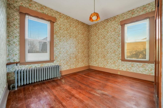 unfurnished room with radiator, wallpapered walls, baseboards, and wood-type flooring