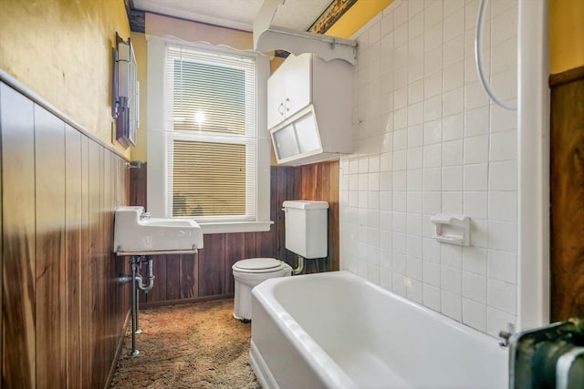 full bathroom with toilet, a tub to relax in, and wood walls