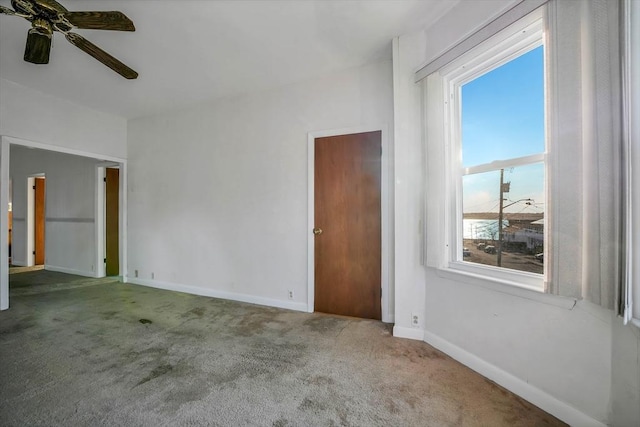 carpeted spare room featuring a ceiling fan and baseboards