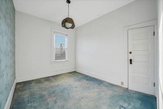 carpeted spare room featuring wallpapered walls and baseboards