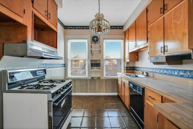 kitchen with dishwasher, light countertops, gas range oven, wainscoting, and a sink