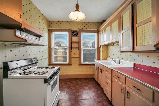 kitchen featuring baseboards, brick patterned floor, white gas range, and wallpapered walls