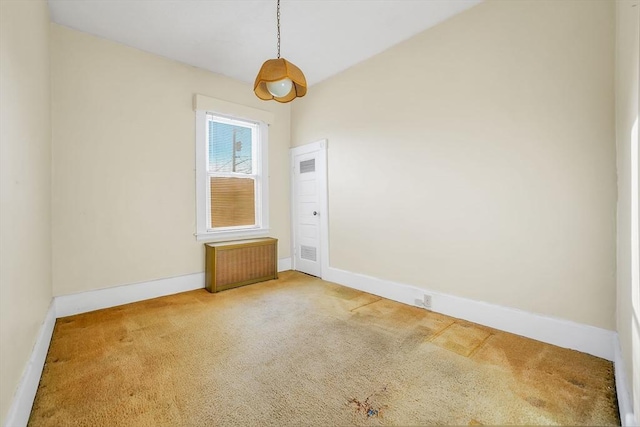 carpeted empty room featuring radiator and baseboards