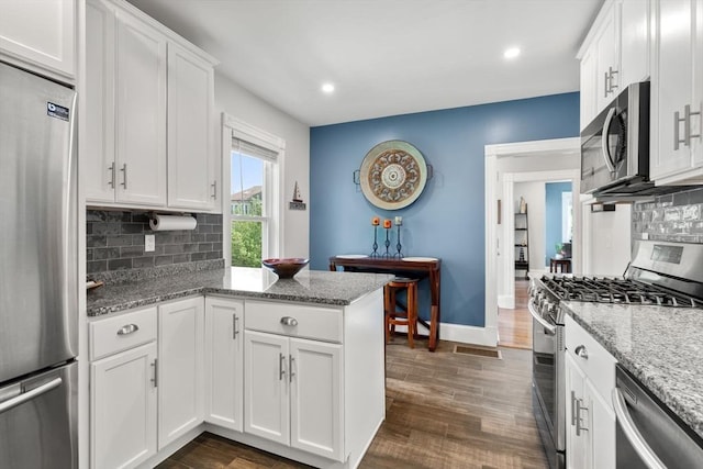 103 Belgrade Ave Unit 2, Boston, MA 02131 - kitchen with stainless steel appliances, a peninsula, white cabinetry, tasteful backsplash, and dark wood-type flooring