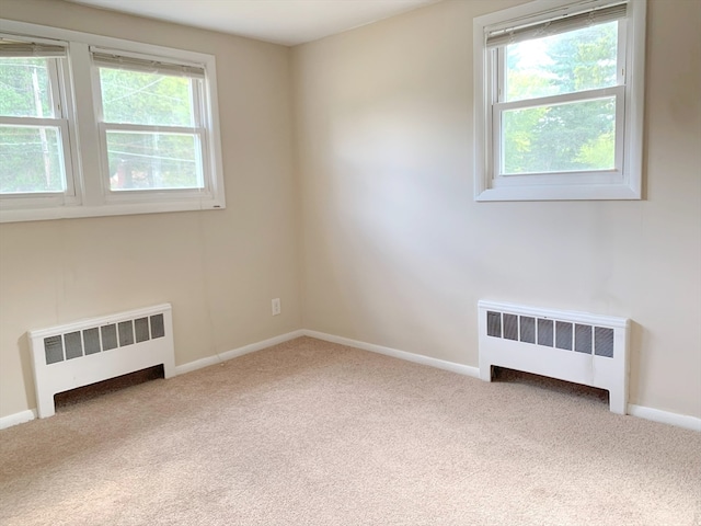 carpeted spare room with radiator heating unit and plenty of natural light