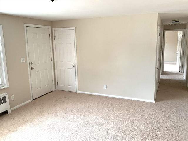 spare room with light carpet and radiator heating unit