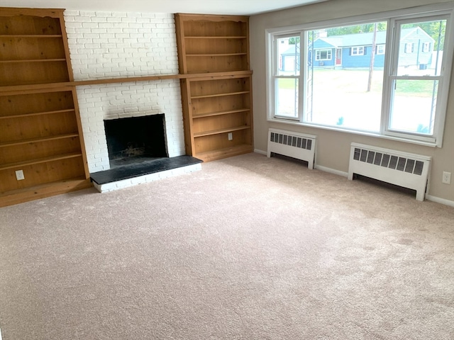 unfurnished living room featuring a fireplace, radiator, carpet, and built in shelves