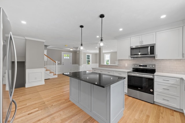 233 W Mountain St, Worcester, MA 01606 - kitchen featuring stainless steel appliances, light wood-style floors, decorative backsplash, crown molding, and white cabinets