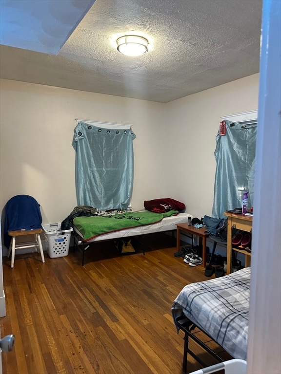 bedroom with dark hardwood / wood-style flooring and a textured ceiling