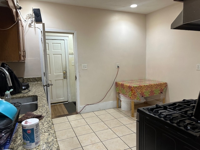 kitchen featuring exhaust hood, black range, sink, light tile patterned flooring, and light stone counters