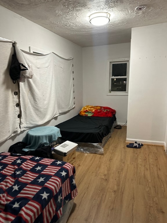 bedroom featuring a textured ceiling and light hardwood / wood-style flooring