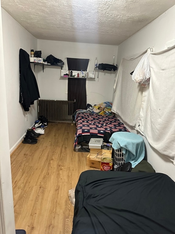 bedroom featuring a textured ceiling, light hardwood / wood-style floors, and radiator