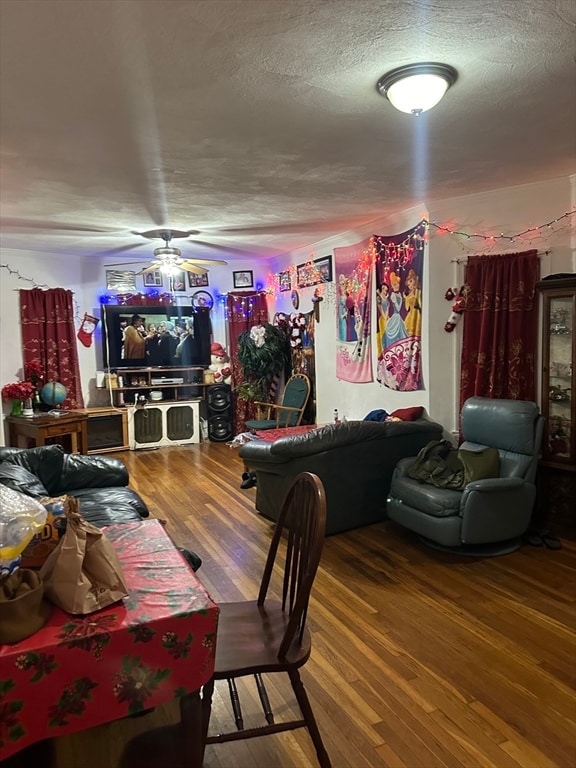 living room with ceiling fan, a textured ceiling, and hardwood / wood-style flooring