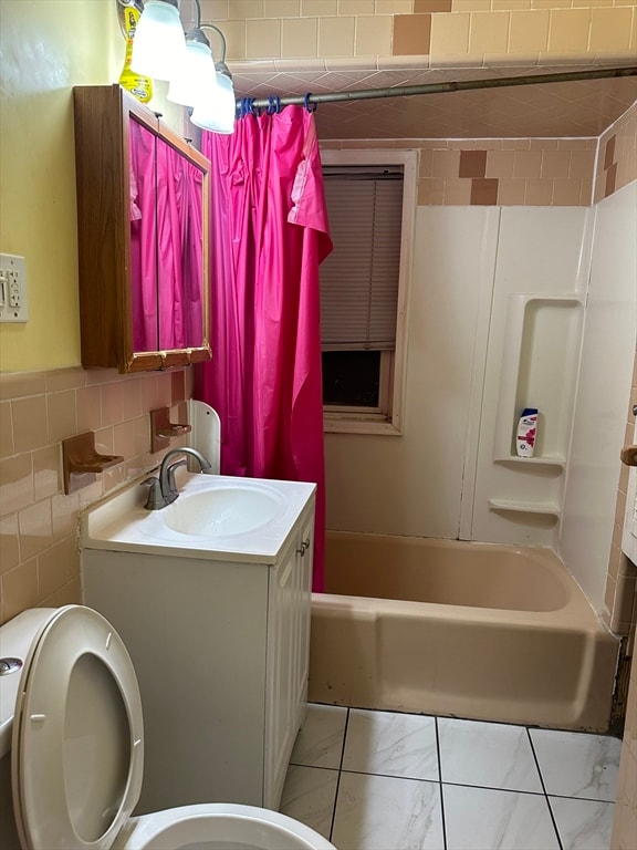 full bathroom with shower / bath combo with shower curtain, vanity, tile walls, and toilet