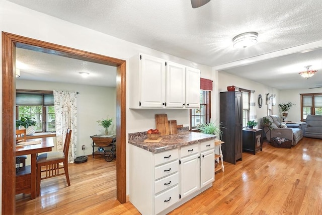 2 Pierce St, Agawam, MA 01030 - kitchen featuring light wood-type flooring, white cabinetry, a textured ceiling, open floor plan, and dark stone counters