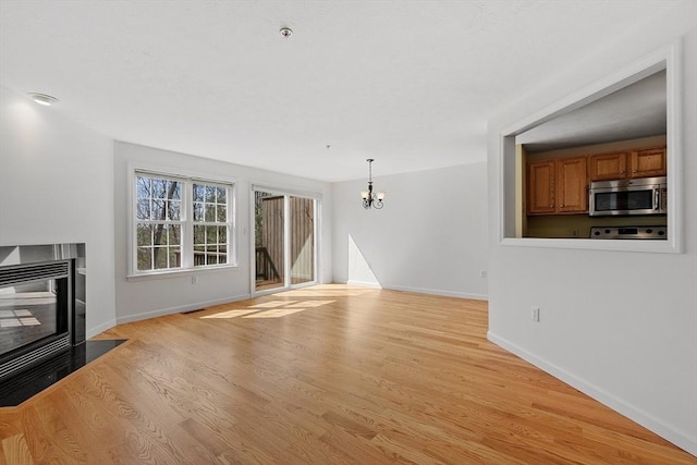98 Caspian Way Unit 98, Fitchburg, MA 01420 - unfurnished living room with a chandelier, light wood-style flooring, baseboards, and a fireplace with flush hearth