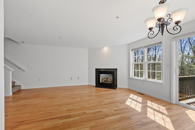 98 Caspian Way Unit 98, Fitchburg, MA 01420 - unfurnished living room featuring visible vents, baseboards, light wood-style flooring, stairs, and a notable chandelier