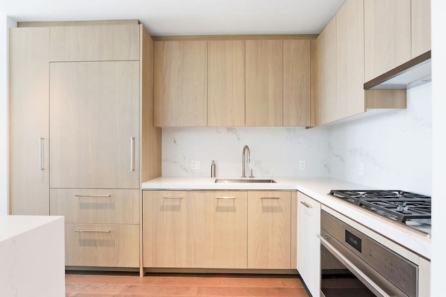 kitchen featuring stainless steel appliances, light hardwood / wood-style floors, light brown cabinets, and sink