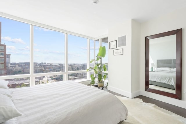 bedroom with wood-type flooring, floor to ceiling windows, and multiple windows