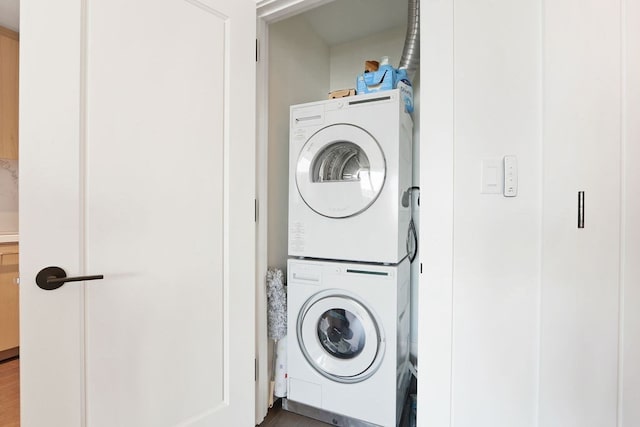 laundry room with stacked washer / dryer and hardwood / wood-style flooring