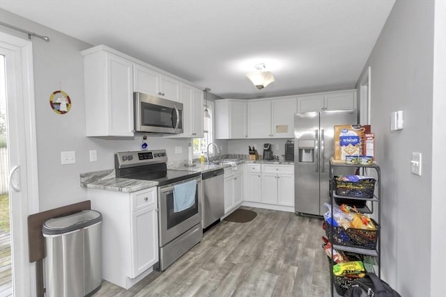 340 Dale St Unit A, Chicopee, MA 01020 - kitchen with a sink, light wood-type flooring, white cabinets, light stone countertops, and appliances with stainless steel finishes