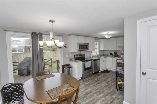 340 Dale St Unit A, Chicopee, MA 01020 - kitchen with light stone countertops, hanging light fixtures, wood finished floors, white cabinets, and appliances with stainless steel finishes